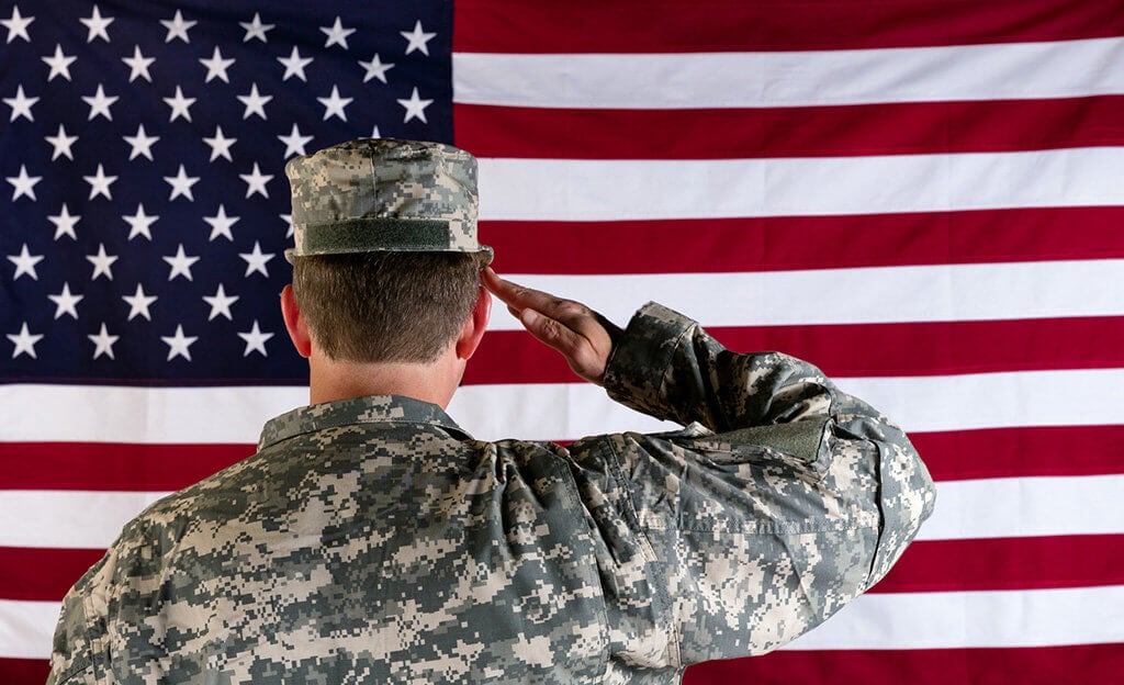 Veteran male solider saluting the flag of USA
