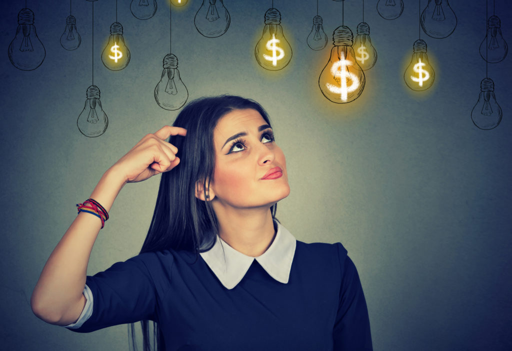 Thinking young woman looking up at dollar idea light bulbs above head