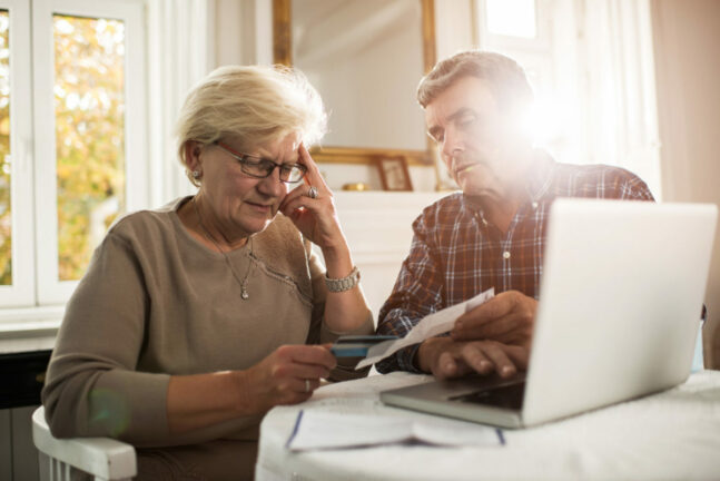 Senior couple sitting at home and having problems with paying their bills.