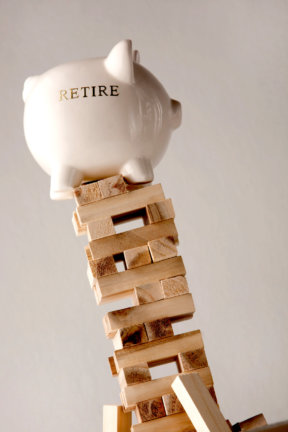 Fear of outliving your retirement savings: people worry their retirement savings won't stand up as symbolized by a piggy bank on a Jenga tower