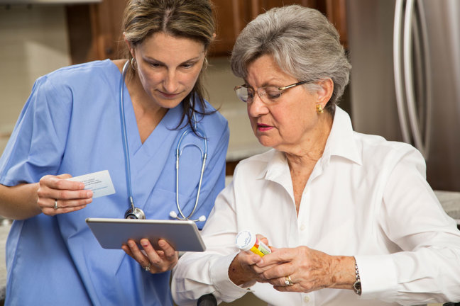 Nurse helps elderly patient understand a prescription