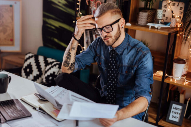 Millennial  sits in front of a computer with financial documents.