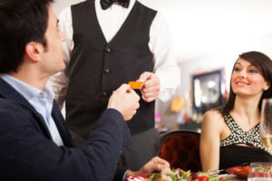 Man paying dinner in a restaurant with a rewards credit card