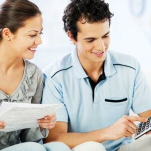 how to build credit; young woman looking at papers, young man with calculator