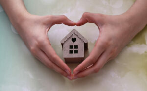 homeowners guide COVID-19; hands making a heart around a small cardboard house