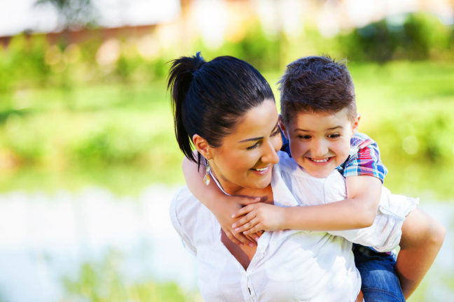 Single Hispanic mother and her son playing piggy back. 