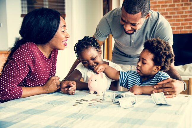 money saving tips for families; man and woman with two young kids counting money with a piggy bank