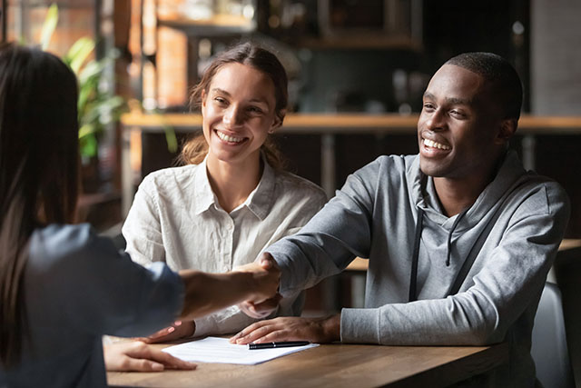 Happy young couple shake hand of bank manager