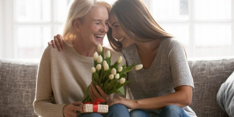 Mother and daughter spending time together on Mother's Day with the daughter handing over a gift and flowers.