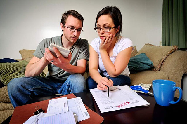 couple on couch with paperwork and calculator