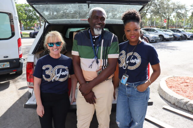 Three people posing together at an outdoor community event
