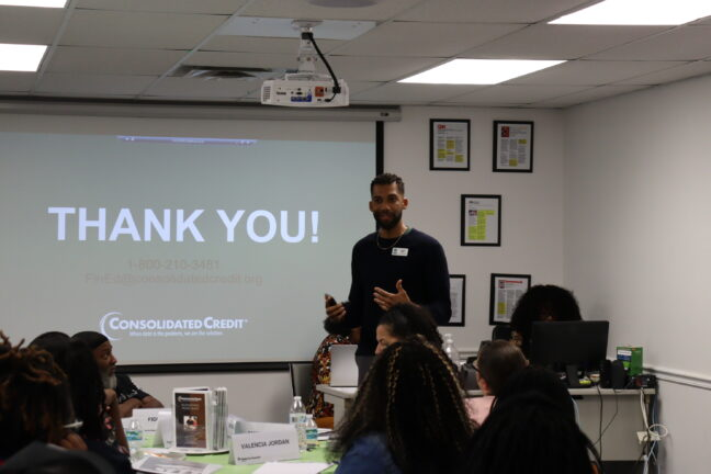 Presenter speaking to an audience in a classroom setting, screen reads "Thank you"