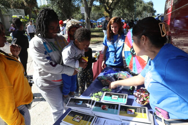 Volunteers handing out materials to visitors at an outdoor booth