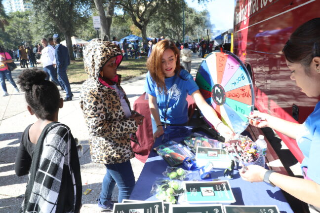 Woman spinning a colorful prize wheel at an event booth