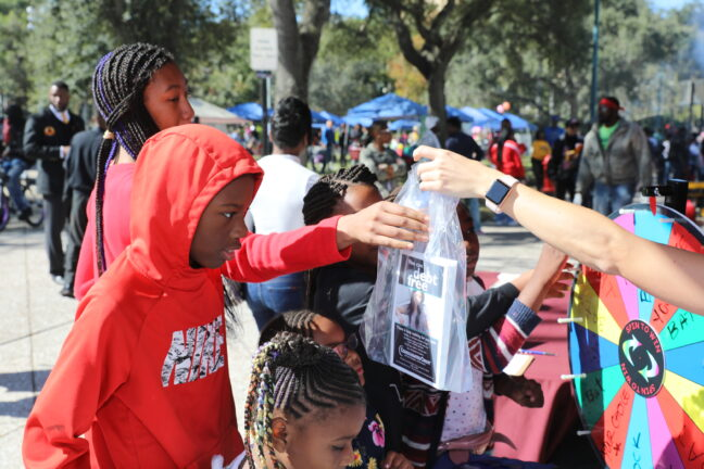 Volunteer handing a bag of supplies to a child outdoors